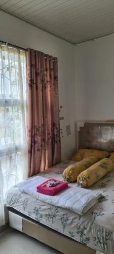 a bed with pillows on it in a room with a window at Bandar Lampung Villa in Kedaton