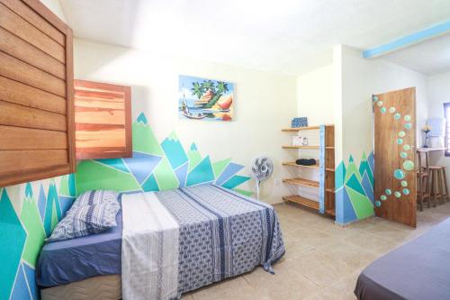 a bedroom with a bed with a blue and green wall at Back to the Beach Hostel - Pipa in Pipa