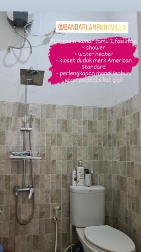 a bathroom with a toilet and a sign on the wall at Bandar Lampung Villa in Kedaton