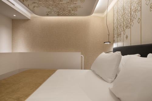a bedroom with a bed with white sheets and pillows at Áurea Palacio de Correos by Eurostars Hotel Company in Logroño