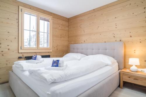 een groot wit bed in een kamer met houten wanden bij Apartment Ahornisegg - GRIWA RENT AG in Grindelwald