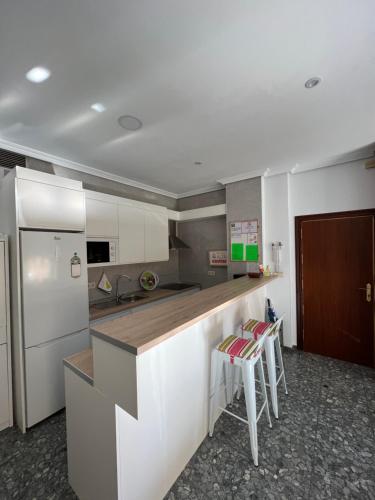 a kitchen with a counter and two stools in it at TORREPEREA- Piso completo in Jaén