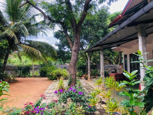 a house with a tree and flowers in the yard at Pawana Rest in Dambulla