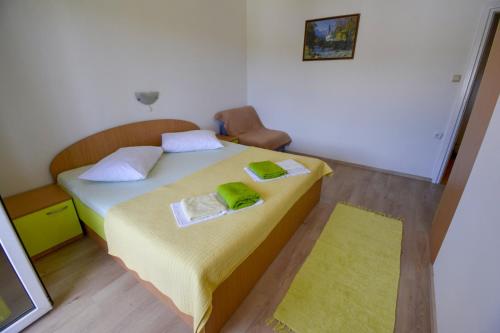 een slaapkamer met een bed met twee groene handdoeken erop bij Apartmani Zlata in Supetarska Draga