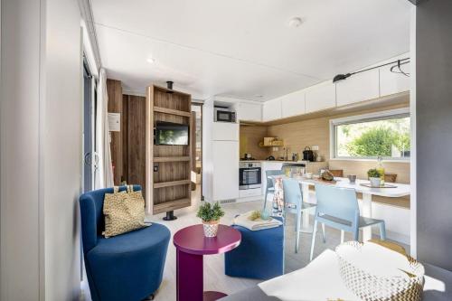 une cuisine et un salon avec des chaises bleues et une table dans l'établissement Vinéa Cottages - Hébergements Touristiques, Terrasse et Piscine privative, à Bourré