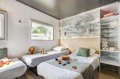 - une chambre avec 3 lits avec des jouets dans l'établissement Vinéa Cottages - Hébergements Touristiques, Terrasse et Piscine privative, à Bourré