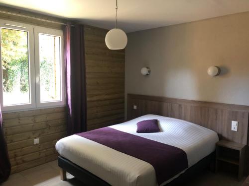 Dormitorio con cama con almohada morada en Logis Hotel Le Val Sarah, en Bardouville