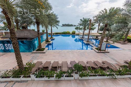 a pool at a resort with palm trees and chairs at Shoreline The Palm, Free beach & pool access in Dubai