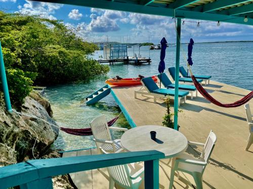 eine Terrasse mit einem Tisch, Stühlen und Wasser in der Unterkunft Vistalmar Ocean Suites in Oranjestad
