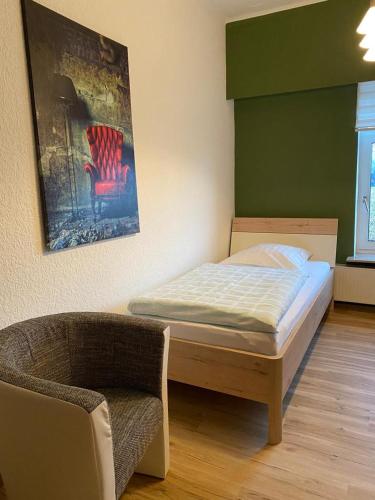 a bedroom with a bed and a chair and a painting at Steimke's Landhotel in Graue