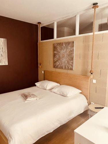 1 dormitorio con 2 camas y almohadas blancas en Suite 24 Appart'hôtel-3 étoiles, en Le Creusot