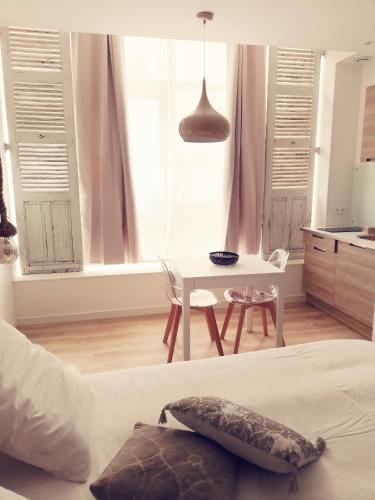1 dormitorio con cama, mesa y cocina en Suite 24 Appart'hôtel-3 étoiles, en Le Creusot