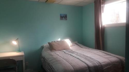 a blue bedroom with a bed and a window at Private Room near Airport in Mississauga