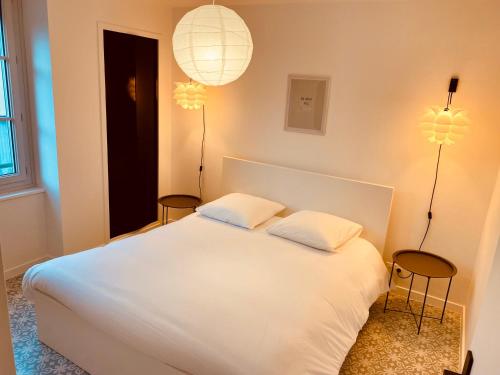 a bedroom with a white bed with two chairs and two lights at Suite 24 Appart'hôtel-L'Annexe-3 étoiles in Montceau-les-Mines