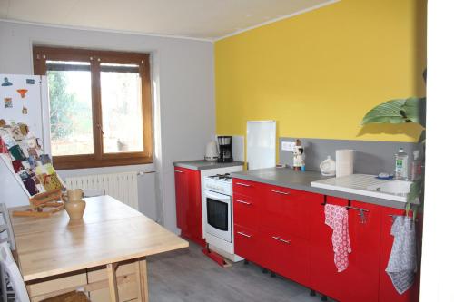 a kitchen with red cabinets and a yellow wall at chez Domi Syl gite nature in Colonne