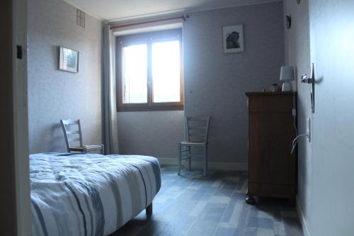 a bedroom with a bed and a window and two chairs at chez Domi Syl gite nature in Colonne
