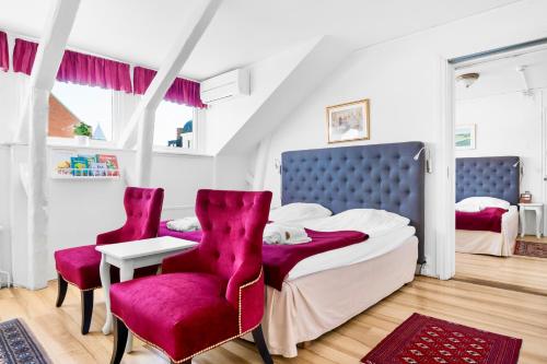 a bedroom with a bed and two red chairs at Hotel Concordia in Lund