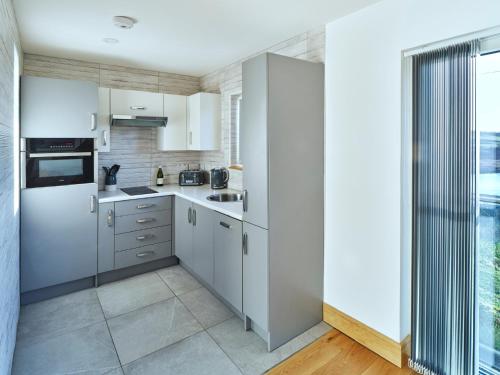 a kitchen with white cabinets and a large window at Red Watch Apartment in Oban