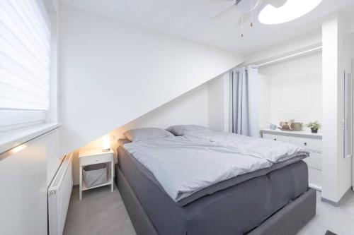 Habitación blanca con cama y ventana en Exklusive (DG) Neubau-Ferienwohnung mit Fernsicht en Konstanz