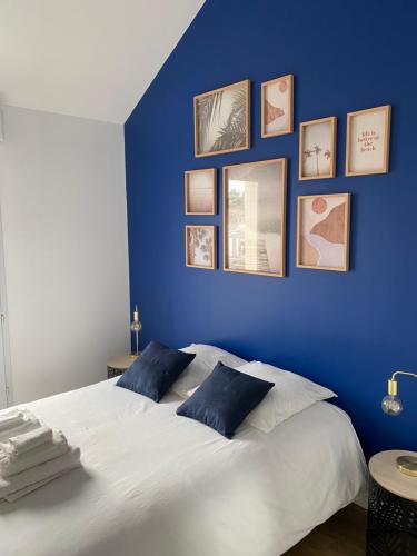 a blue bedroom with a white bed with pictures on the wall at Sacré cœur - Duplex avec balcon - 4 pers in Cholet