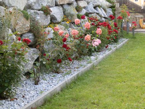 a garden of flowers with rocks and roses at Ferienwohnungen Trinker - Lungau Karte inklusive in Ramingstein