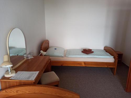 a bedroom with a bed and a desk and a mirror at Penzion Stella in Luhačovice