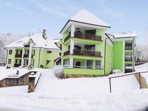 a green apartment building with snow on the ground at Penzion Stella in Luhačovice