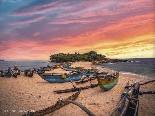 three boats sitting on the beach at sunset at Muru's Place in Dickwella