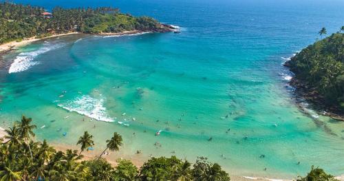 an aerial view of a beach with people in the water at Muru's Place in Dickwella