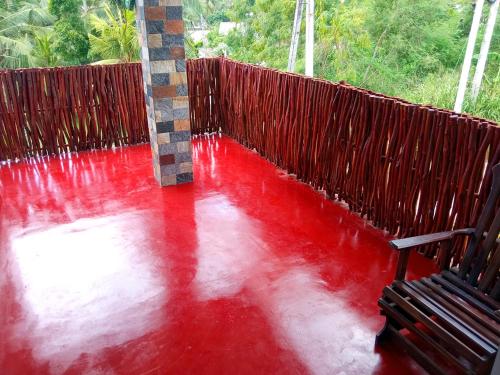 a red floor with a fence and a bench at Muru's Place in Dickwella