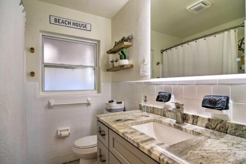 a bathroom with a sink and a toilet and a mirror at Lush Seminole Surf Inn with Backyard Fire Pit! in Seminole