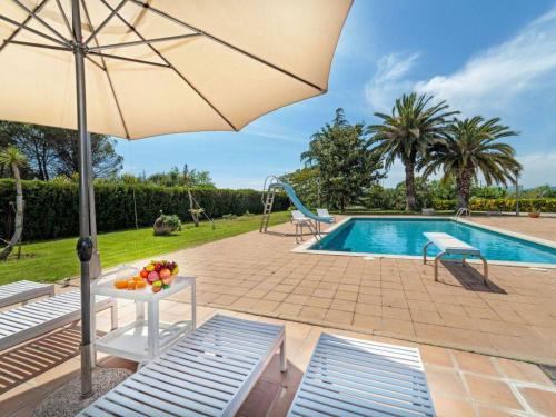 una piscina con sombrilla y una mesa con fruta. en Casa Rustica con piscina en Girona, en Fornells de la Selva