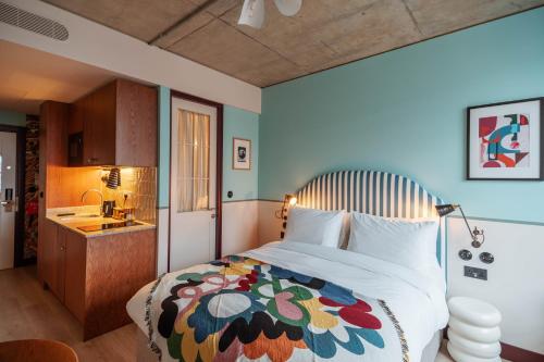um quarto com uma cama grande e um cobertor colorido em room2 Chiswick Hometel em Londres