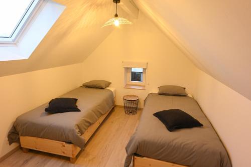 two beds in a attic room with a window at L’annexe in Huy