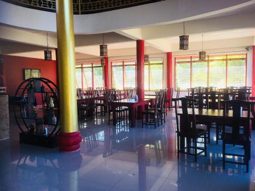 una sala da pranzo con tavoli, sedie e finestre di The Natural Yurt Resort @ Khao Kho a Khao Kho