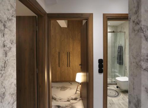 a bathroom with a toilet and a glass door at LA Larissa Luxury Apartments Kreousa in Larisa