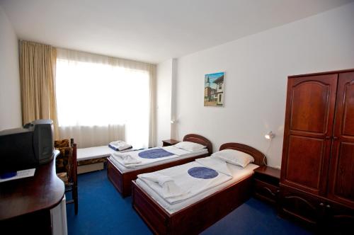 a hotel room with two beds and a tv at Семеен Хотел Елена Палас in Nesebar