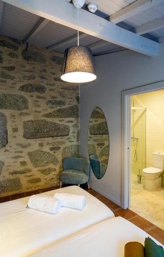 a bedroom with a bed and a chair and a wall at Quinta De Vila Nova - Agroturismo in Monção