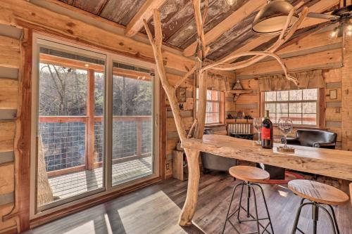 Cabaña de madera con cocina con mesa y taburetes en Hand-Crafted Creekside Treehouse with Grill!, en Cosby
