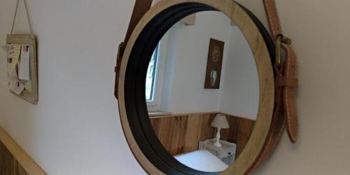 espejo redondo con marco de madera en la pared en Chambres d'hôtes La Combe de Redoles en Tour-de-Faure