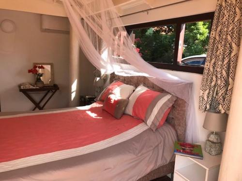 1 dormitorio con 1 cama con almohadas rojas y blancas en Flamingo Sunsets Apartment, en Willebrordus