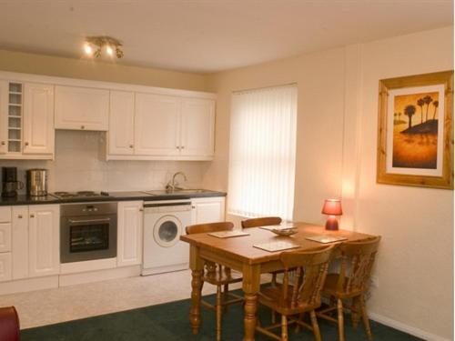 una cucina con un tavolo di legno e un tavolo e sedie di Arrandale House a Douglas