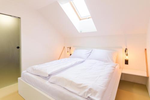 a white bed in a room with a skylight at Coffein apartments in Mostkovice