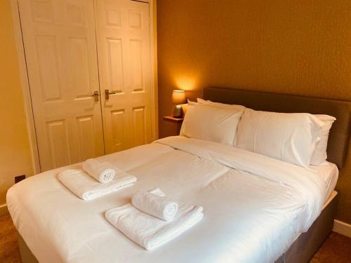 białe łóżko z dwoma składanymi ręcznikami w obiekcie Comfy House with Parking for Multiple Vehicles w Cardiff