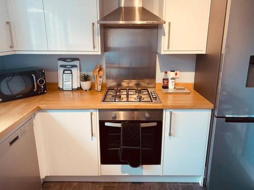 cocina pequeña con fogones y microondas en Comfy House with Parking for Multiple Vehicles, en Cardiff