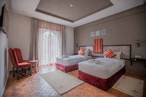 um quarto de hotel com duas camas e uma cadeira em Dar Ba Sidi & Spa em Chefchaouene