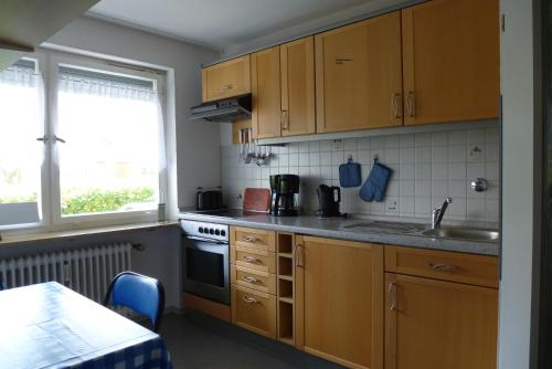 a kitchen with wooden cabinets and a sink and a stove at Gästehaus Moleblick in Uhldingen-Mühlhofen