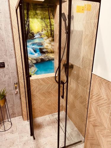 a shower with a waterfall mural on the wall at Apartamenty KTW Park Śląski in Katowice