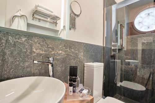 a bathroom with a sink and a toilet and a clock at The Rif - Boutique Hotel in Pisa