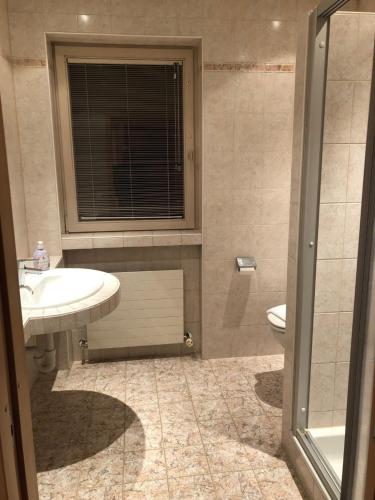 a bathroom with a sink and a toilet and a window at Sportpension Therese in Westendorf